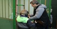 Mężczyzna na strzelnicy w straży granicznej przygotowuje dziecku broń do strzelania do celu.